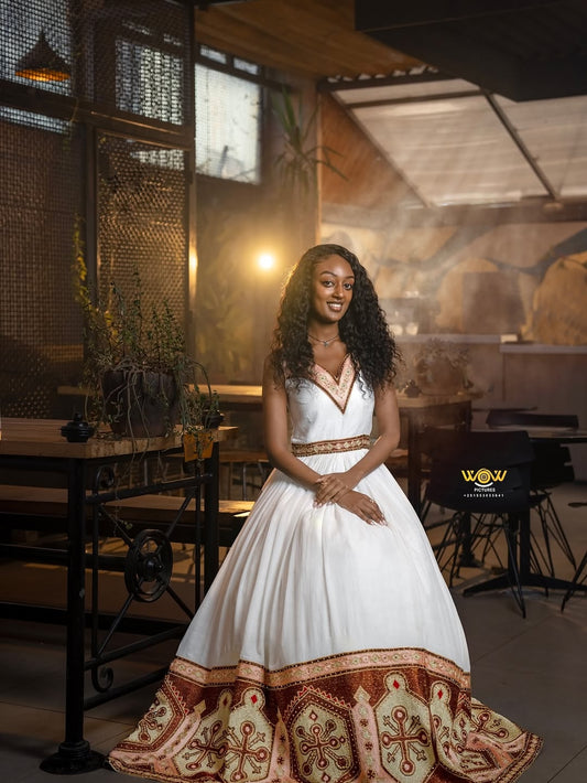 Woman in a white dress with red patterns standing in a restaurant setting