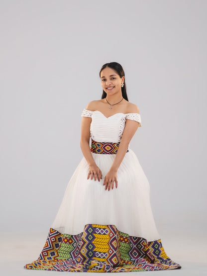 Woman in a white and green habesha dress in an elegant interior setting.