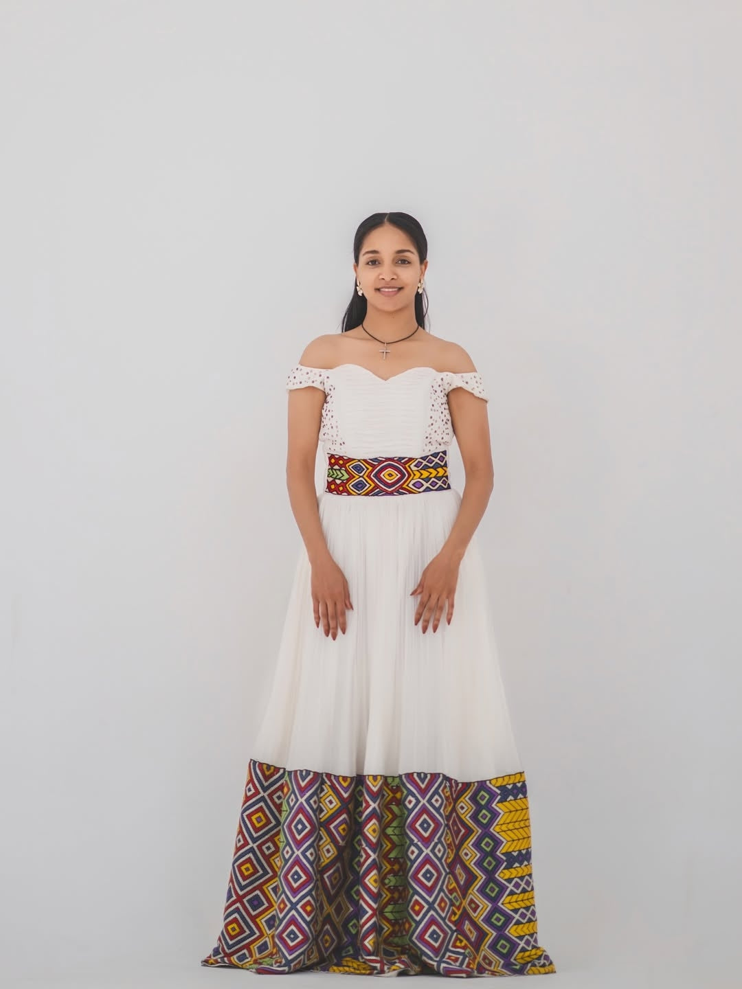 Woman in a white and gold habesha dress in an elegant interior setting.