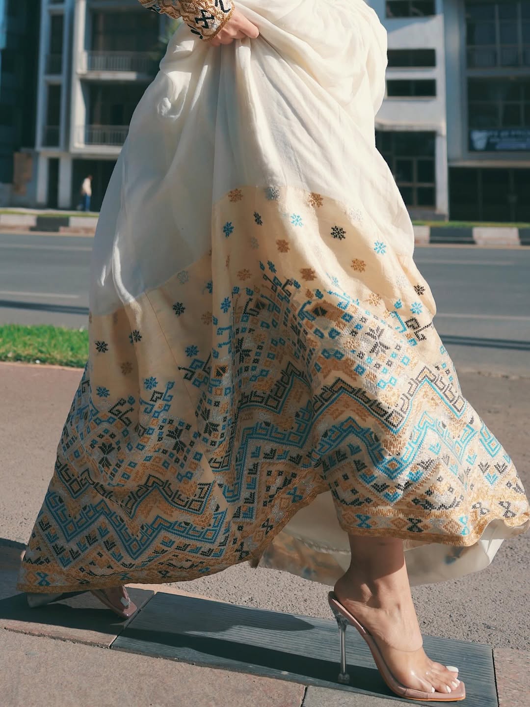 Person wearing a long, patterned skirt with a blurred urban background