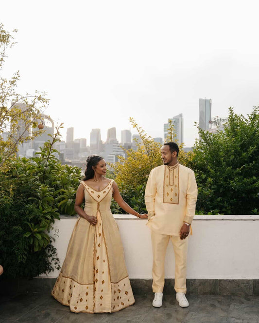 Couple in formal Habesha matching couple outfit standing on a rooftop with city skyline in the background