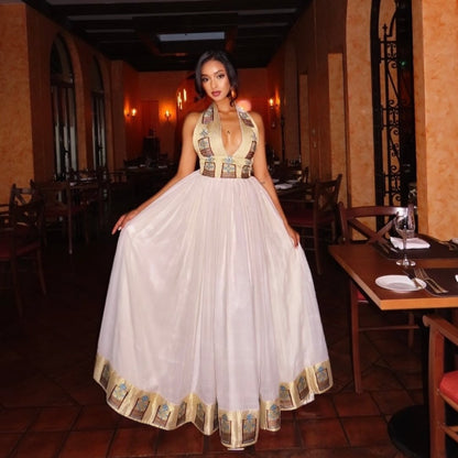 Woman in a long, elegant Ethiopian Clothing standing in a restaurant setting