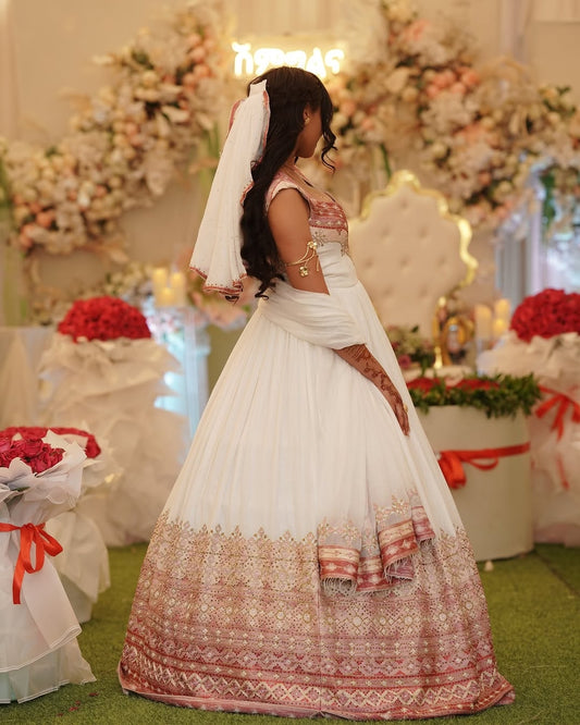 Woman in a traditional white and red bridal Pink Ethiopian Wedding Dress with floral decorations in the background