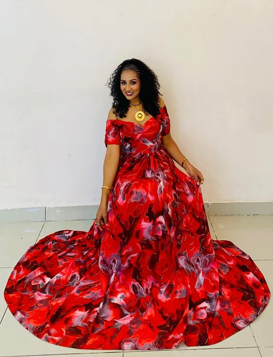 Woman wearing a red floral dress against a white wall
